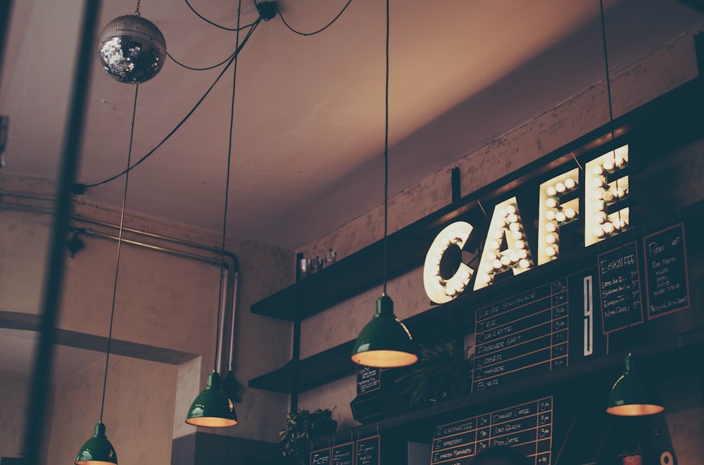 Koselig kaféinteriør med opplyst CAFE-skilt og pendellamper